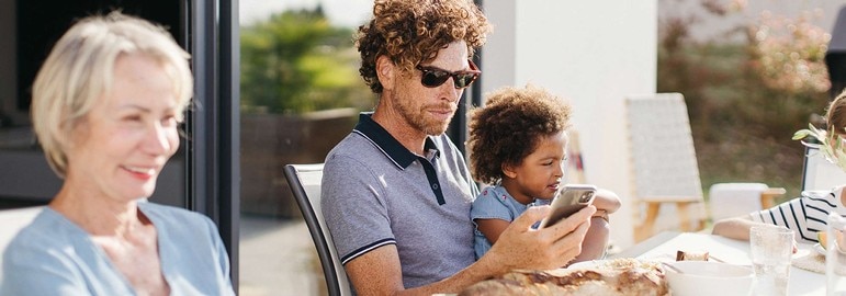 somfy-family-eating-on-terrace-man-using-smartphone
